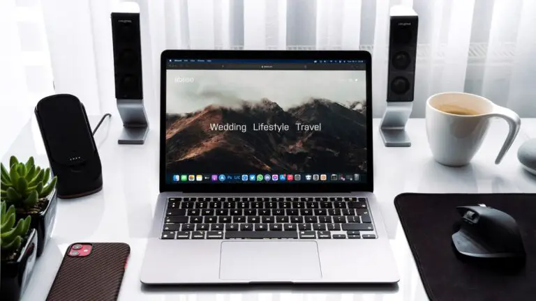 macbook pro beside white ceramic mug