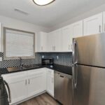 silver top mount refrigerator beside white wooden kitchen cabinet