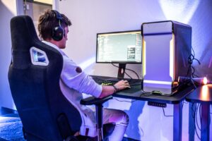 a man sitting in front of a gaming computer on a desk