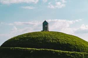 quiet white and black house on green hill under white clouds and blue sky during daytime