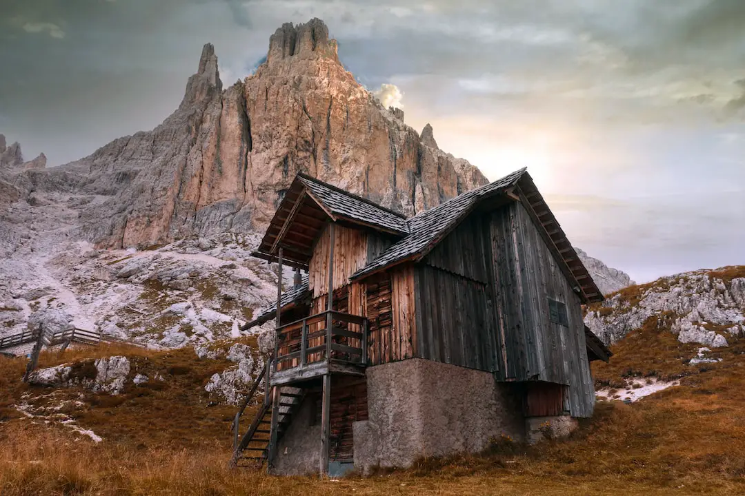 an old wooden building with a mountain in the background