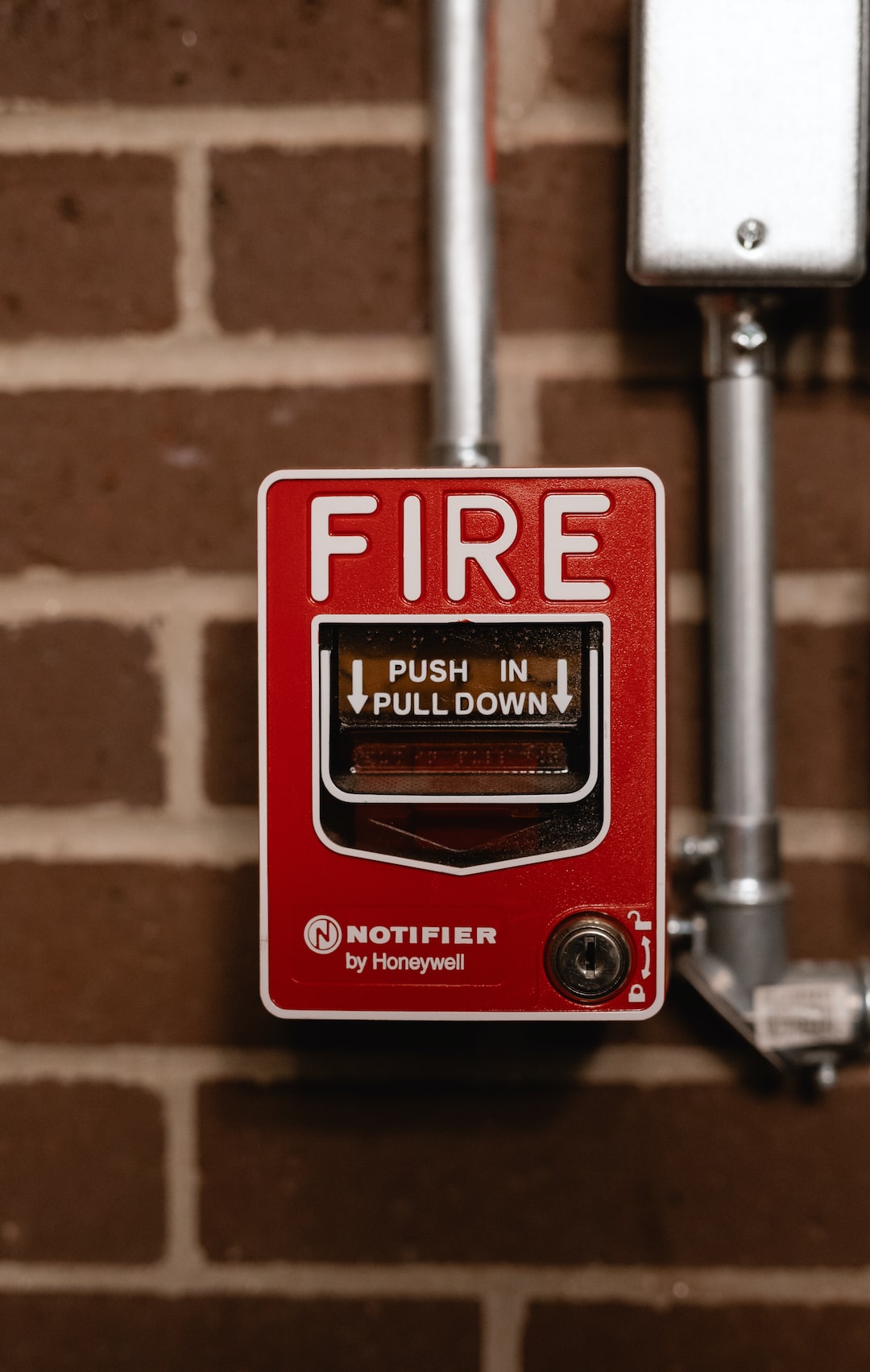 a red fire button on a brick wall