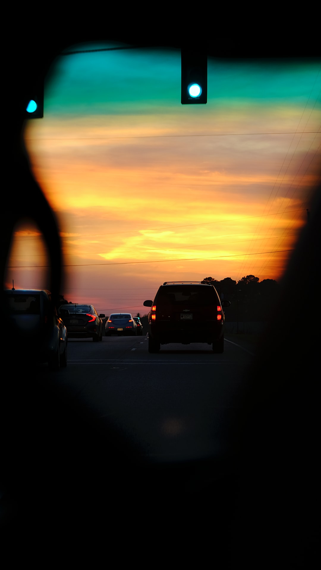 a sunset seen through a car's rear view mirror